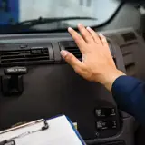 person with hand over heat vent in truck